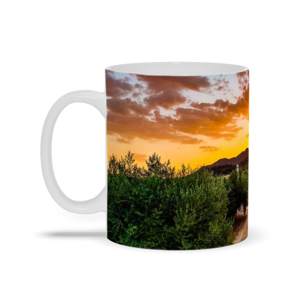 11oz ceramic coffee mug featuring Sam Gilliss' "Sunset Over the Olive Groves" artwork, showcasing a scenic Central Spain countryside.